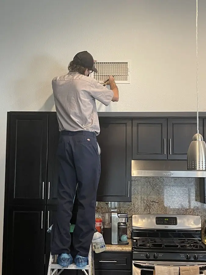 Technician inspecting an air vent during HVAC service in Cascades